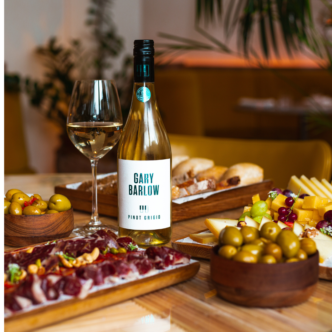 Gary Barlow Pinot Grigio paired with charcuterie, cheese, olives, and bread, highlighting its perfect match for fine dining.